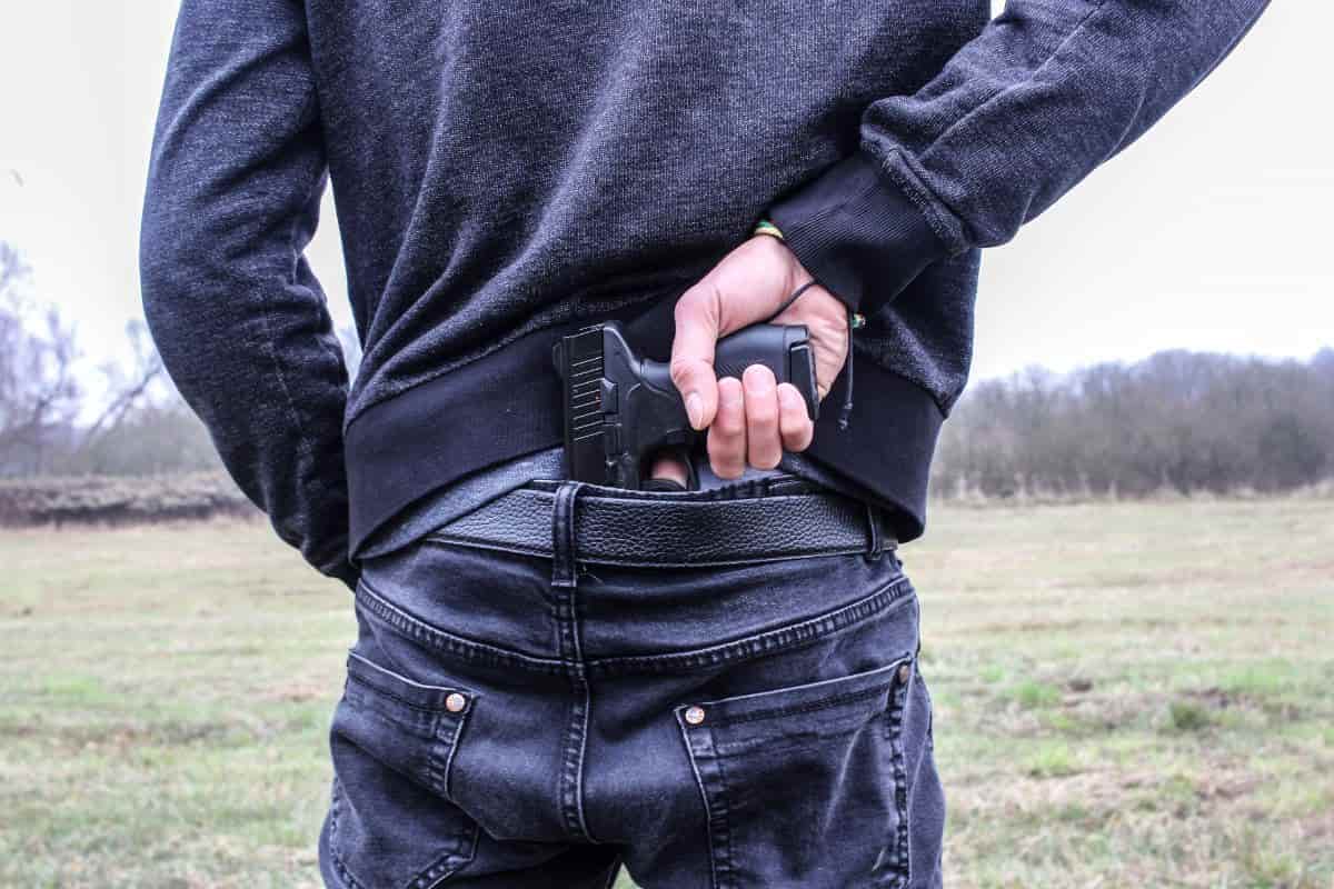 ragazzo che prende la pistola da dietro la schiena nei pantaloni